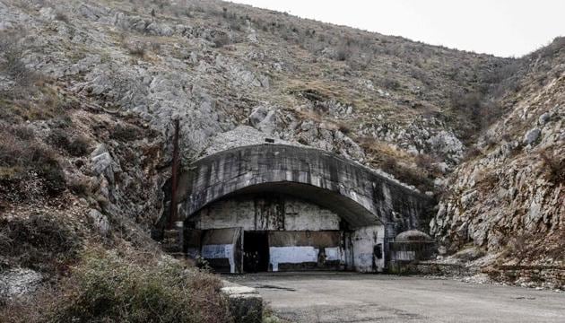 General view of the entrance of the main tunnel of the Gjader Air Base built near the city of Lezhe, on February 5, 2019. - On a barren hillside in northern Albania lies a portal to the country's communist past: a massive steel door creaks open to reveal a hidden former air base burrowed into the heart of the mountain. Made up of 600 metres (1,980 feet) of tunnels that once teemed with military life, the secret Gjader air base is now a depot for dozens of hulking communist-era MiG jets collecting dust in the darkness. Three decades after shedding communism, Albanian authorities are still trying to sell off the Soviet and Chinese-made aircraft, of which there are dozens more in another nearby air base.(AFP)