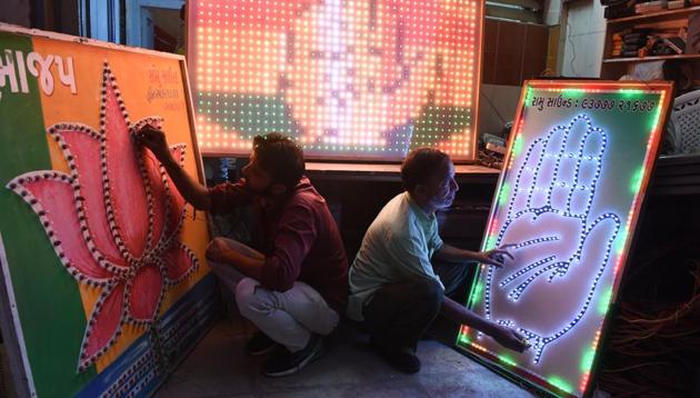 Men check electrical lighting signboard of Congress and BJP at a workshop in Ahmedabad on April 3.(AFP Photo) Men check electrical lighting signboard of Congress and BJP at a workshop in Ahmedabad on April 3.(AFP Photo)