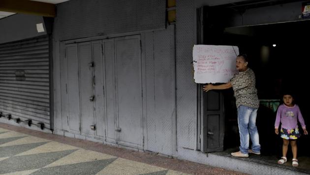 Surrounded by shuttered shops, Rosa Luque hangs a list of her menu’s offerings: beef, pork, liver, chicken and meatballs, as she opens her restaurant. The sign reads in Spanish: “Yes there’s lunch,” and lists prices around a dollar. (Natacha Pisarenko / AP) Surrounded by shuttered shops, Rosa Luque hangs a list of her menu’s offerings: beef, pork, liver, chicken and meatballs, as she opens her restaurant. The sign reads in Spanish: “Yes there’s lunch,” and lists prices around a dollar. (Natacha Pisarenko / AP)