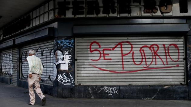 The Spanish words “It rotted” cover a shuttered shop. Many storefronts are just graffiti-scrawled security doors chained shut. Often just a single business along a city block is able to stay open, awaiting sparse customers. Others close earlier, like a beauty salon, its few remaining clients forced to decide between the simple luxury of haircut or buying food. (Natacha Pisarenko / AP) The Spanish words “It rotted” cover a shuttered shop. Many storefronts are just graffiti-scrawled security doors chained shut. Often just a single business along a city block is able to stay open, awaiting sparse customers. Others close earlier, like a beauty salon, its few remaining clients forced to decide between the simple luxury of haircut or buying food. (Natacha Pisarenko / AP)