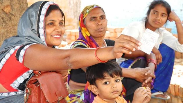 Shaina Rajput of village Nagla Arhar smiles as she holds up her newly obtained voter ID.(Raju Tomar / HT Photo)