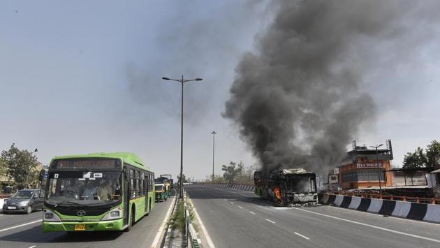 A Delhi Transport Corporation bus passes by another that caught fire at Hanuman Temple near Kashmiri Gate in New Delhi. (Sanchit Khanna / HT Photo) A Delhi Transport Corporation bus passes by another that caught fire at Hanuman Temple near Kashmiri Gate in New Delhi. (Sanchit Khanna / HT Photo)