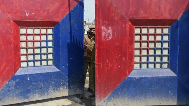 A policeman looks out from a gate of a central jail in Srinagar, Jammu and Kashmir. Riots broke out after rumours started floating that some inmates were being shifted out of the Kashmir valley. The inmates burnt a temporary shelter and tried to come to the outer cordon of the jail located in the downtown area of the city. (Tauseef Mustafa / AFP) A policeman looks out from a gate of a central jail in Srinagar, Jammu and Kashmir. Riots broke out after rumours started floating that some inmates were being shifted out of the Kashmir valley. The inmates burnt a temporary shelter and tried to come to the outer cordon of the jail located in the downtown area of the city. (Tauseef Mustafa / AFP)