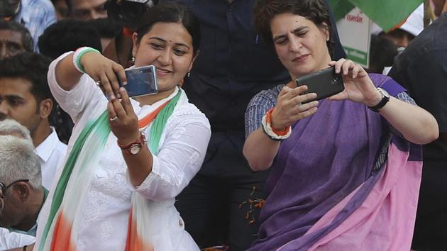 Congress general secretary Priyanka Gandhi Vadra, right, and Congress candidate for Ghaziabad Dolly Sharma, left, take selfies for supporters during a roadshow in Ghaziabad, Friday, April 5, 2019.(AP)