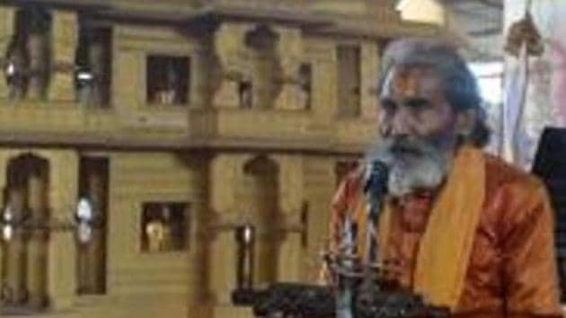 A sadhu worships as he sits next to a model of the proposed temple at Ram Janmabhoomi Nyas workshop at Ayodhya in Uttar Pradesh.(AFP file)