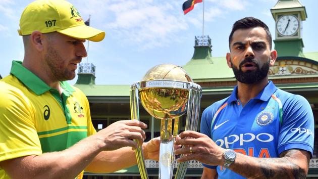 Virat Kohli (R) and his Australian counterpart Aaron Finch pose with the ICC Cricket World Cup trophy.(AFP)