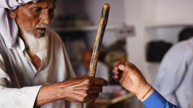 A polling officer puts an indelible ink mark on the index finger of a voter, at Kawal village, in Muzaffarnagar district, Uttar Pradesh. Yesterday’s voting was held across 18 states and two Union territories. (Vipin Kumar / HT Photo)