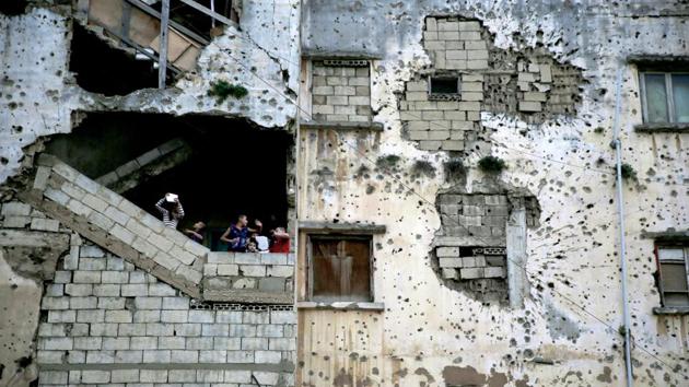 Syrian refugee children stand on the stairs of their apartment in a building on a former Beirut frontline. There are a few remaining residential buildings located along the former Green Line, which separated the mainly Muslim part of West Beirut from the predominantly Christian part, their ravaged facades a testimony to the horrors witnessed many years ago. (Hassan Ammar / AP)