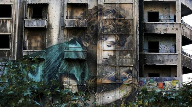 Graffiti by Cuban-American artist Jorge Rodriguez-Gerada depicting a boy is painted on a bullet riddled building. The buildings still stand, either because their owners have no money to fix them, or because of disputes over ownership. “Seeing these buildings is like being slapped in the face,” said Sahar Mandour, a Lebanese journalist and a writer. (Hassan Ammar / AP)