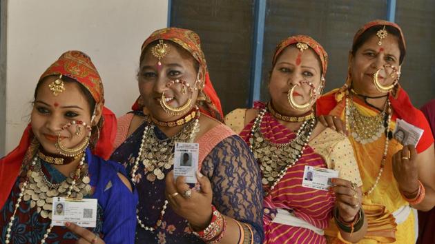 Women voters dressed in their traditional attire show their identity cards as they stand in a queue at a polling station to cast their votes during the first phase of the general elections, in Dehradun, Thursday, April 11, 2019.(PTI)