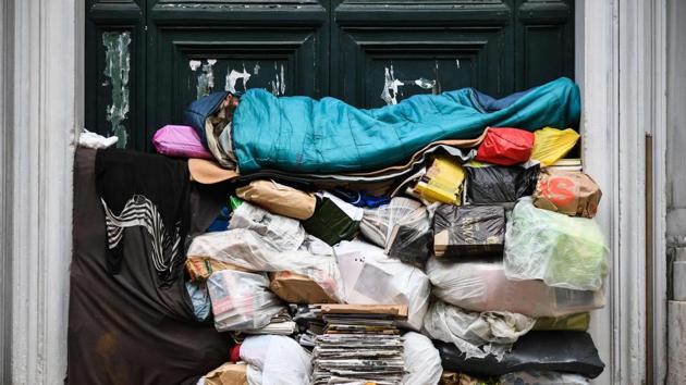A homeless man sleeps on a pile of plastic bags and newspapers under a porch in Rome, Italy. (Vincenzo Pinto / AFP) 