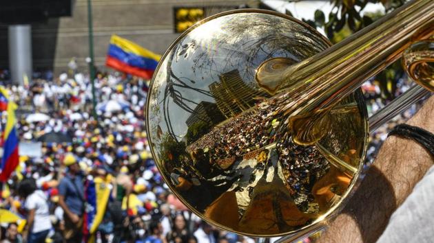 Supporters of Venezuelan opposition leader and self-proclaimed interim president Juan Guaido are reflected on a trumpet during a demo in Caracas, Venezuela. (Matias Delacroix / AFP) 
