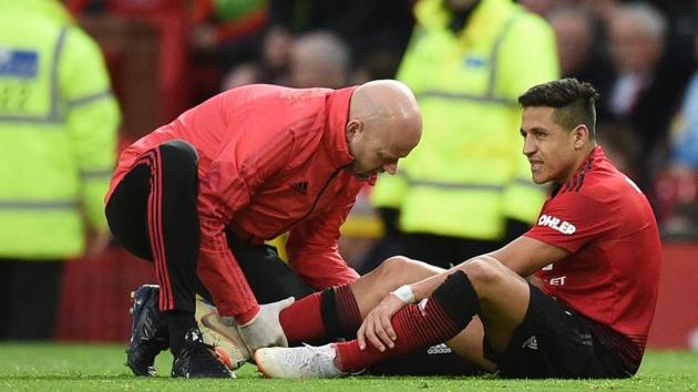 TOPSHOT - Manchester United's Chilean striker Alexis Sanchez (R) receives medical attention after picking up an injury during the English Premier League football match between Manchester United and Southampton at Old Trafford in Manchester, north west England, on March 2, 2019.(AFP)