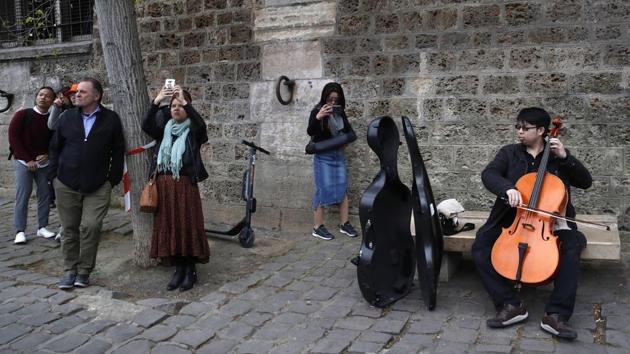 A man plays violoncello as people come to watch and photograph the Notre Dame after the fire on April 16, 2019. (Christophe Ena / AP) A man plays violoncello as people come to watch and photograph the Notre Dame after the fire on April 16, 2019. (Christophe Ena / AP)