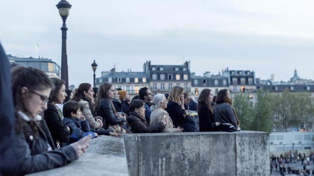 Parisians had gathered to say prayers and sing hymns In front of the nearby Saint Julien Les Pauvres church as the massive blaze burned only a few hundred meters away. A couple hundred people knent in prayer at the center of a larger group, who were standing around the edge and joining in the hymns between the prayers. (Martin Barzilai / Bloomberg) Parisians had gathered to say prayers and sing hymns In front of the nearby Saint Julien Les Pauvres church as the massive blaze burned only a few hundred meters away. A couple hundred people knent in prayer at the center of a larger group, who were standing around the edge and joining in the hymns between the prayers. (Martin Barzilai / Bloomberg)
