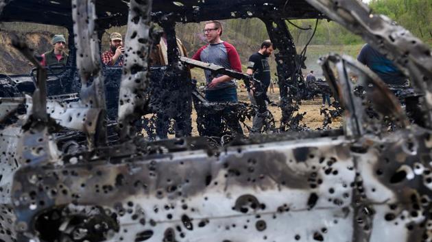 People look at a destroyed car on the main firing line. Kenny Sumner is the current owner and manager of the Knob Creek Gun Range. (Andrew Caballero-Reynolds / AFP)