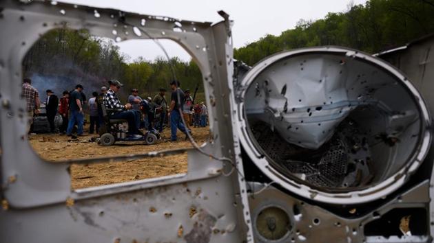 Visitors explore destruction on the main firing line during a break. At the Military Gun Show that accompanies the shoot, vendors sell everything from guns to ammunition. An extensive amount of German World War II memorabilia is also on offer. (Andrew Caballero-Reynolds / AFP)