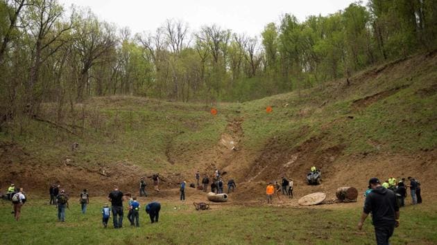 Visitors climb the hills at the back of the main firing line looking for souvenirs during a break in the shooting. The rapid fire thumping of automatic gunfire is never far away as machine guns riddle abandoned cars, old appliances and other targets with bullet holes at the Knob Creek Gun Range. (Andrew Caballero-Reynolds / AFP)