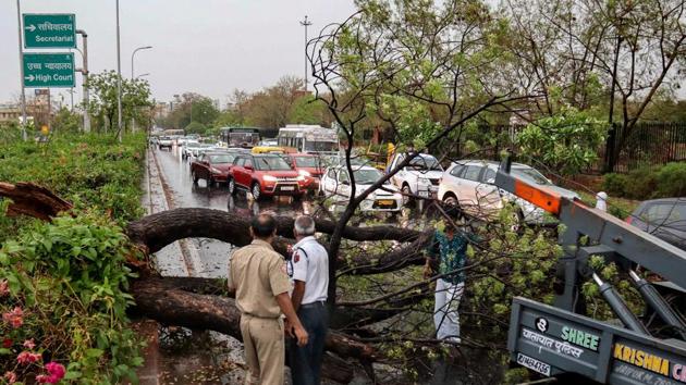 Jaipur: Police personnel look on as people remove a fallen tree obstructing traffic, after a thunderstorm, in Jaipur, Tuesday, April 16, 2019.(PTI) Jaipur: Police personnel look on as people remove a fallen tree obstructing traffic, after a thunderstorm, in Jaipur, Tuesday, April 16, 2019.(PTI)