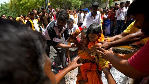 A devotee holds her son as she walks on the burning pit to mark the 'Thimithi' festival at Shakurpur, in New Delhi. (Amal KS / HT Photo) A devotee holds her son as she walks on the burning pit to mark the 'Thimithi' festival at Shakurpur, in New Delhi. (Amal KS / HT Photo)