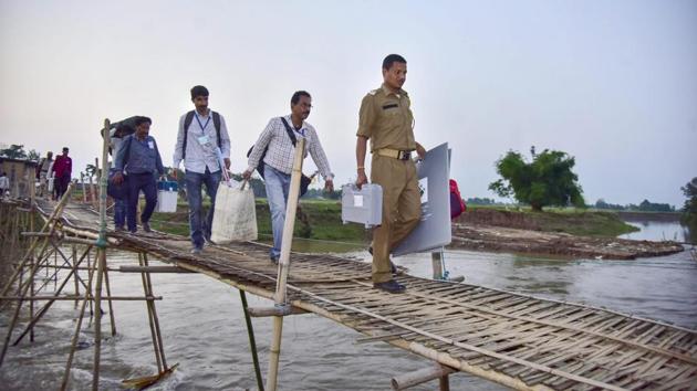 Election staff carry VVPAT machines and an EVM as they cross a bamboo bridge to reach remote polling stations ahead of second phase of general elections, at Soraijuria village in Nagaon, Assam. (PTI) Election staff carry VVPAT machines and an EVM as they cross a bamboo bridge to reach remote polling stations ahead of second phase of general elections, at Soraijuria village in Nagaon, Assam. (PTI)