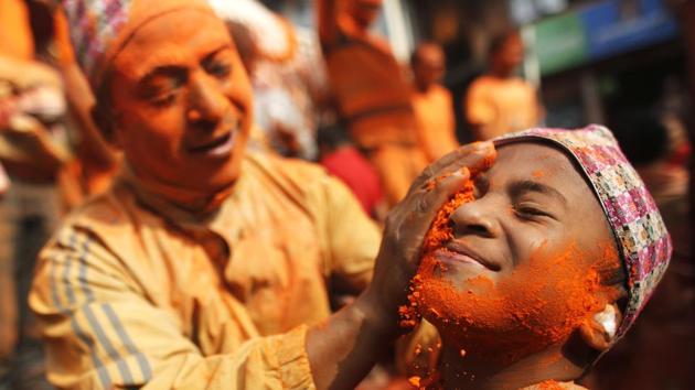 A Nepalese man smears ‘sindoor’ or vermillion powder, to a boy during Sindoor Jatra festival in Bhaktapur, Nepal. Devotees mark the festival by playing traditional drums, singing, dancing and carrying chariot of various deities around town while throwing sindoor to welcome the advent of spring and the New Year. (Niranjan Shrestha / AP) 