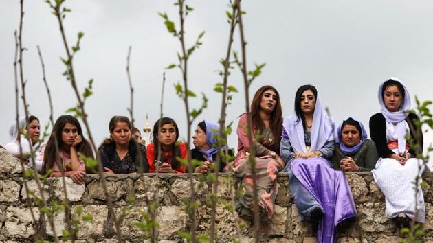 Iraqi Yazidi women sit outside the Temple of Lalish, in a valley near the Kurdish city of Dohuk about 430 kilometres northwest of the capital Baghdad, during a ceremony marking the Yazidi New Year. (Safin Hamed / AFP) 
