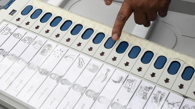 An election official examines an EVM at a distribution centre.(AFP)