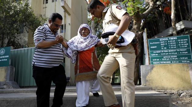 A police official and a citizen help a physically challenged elderly citizen, at a polling centre near Salisbury Park, in Pune. (Rahul Raut/HT PHOTO) 