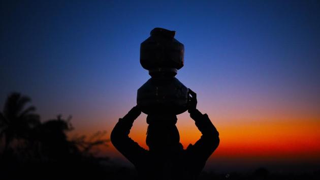 A woman carries pots of drinking water in Ghanichamata area in Dindori. Less than 25kms from Nashik city, Ghanichamata, on the outskirts of Dindori village, which is grappling with drought, a single hand pump caters to nearly 5,000 residents. Every day for the past 10 years, women here have braving heat and never-ending queues, sometimes for four to five hours for drinking water. (Pramod Thakur / HT Photo)