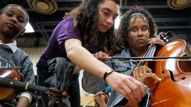 Mentor Carolyn Rosinsky (C) helps tune a cello for Stefany Carbaja. The program offers them a safe place to go after school without charge -- easing the minds of busy parents who would otherwise need child care or leave children unsupervised. “We’re providing not only academic support but also a healthy snack and a dinner before they go home,” Skinner explained. (Jim Watson / AFP) Mentor Carolyn Rosinsky (C) helps tune a cello for Stefany Carbaja. The program offers them a safe place to go after school without charge -- easing the minds of busy parents who would otherwise need child care or leave children unsupervised. “We’re providing not only academic support but also a healthy snack and a dinner before they go home,” Skinner explained. (Jim Watson / AFP)
