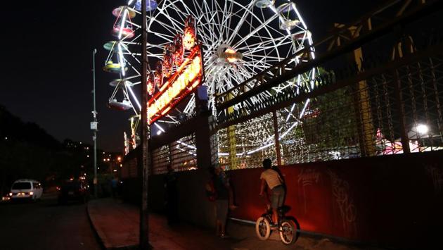 A child climbs on a bike to see an amusement park with an illuminated ferris wheel in Caracas. Venezuela was plunged into darkness with two massive blackouts in March, generating water shortages and prompting the government to suspend work and school. Earlier this month, the government launched a power rationing plan, and electricity remains intermittent. (Ivan Alvarado / REUTERS) A child climbs on a bike to see an amusement park with an illuminated ferris wheel in Caracas. Venezuela was plunged into darkness with two massive blackouts in March, generating water shortages and prompting the government to suspend work and school. Earlier this month, the government launched a power rationing plan, and electricity remains intermittent. (Ivan Alvarado / REUTERS)