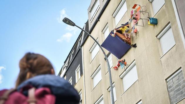 A passerby watches an actor of the French street theatre company Royal de Luxe known as ‘Monsieur Bourgogne’ as he sits in his tent on the facade of a building in the Bellevue neighbourhood in Saint-Herblain, near Nantes, France. (Loic Venance / AFP) A passerby watches an actor of the French street theatre company Royal de Luxe known as ‘Monsieur Bourgogne’ as he sits in his tent on the facade of a building in the Bellevue neighbourhood in Saint-Herblain, near Nantes, France. (Loic Venance / AFP)