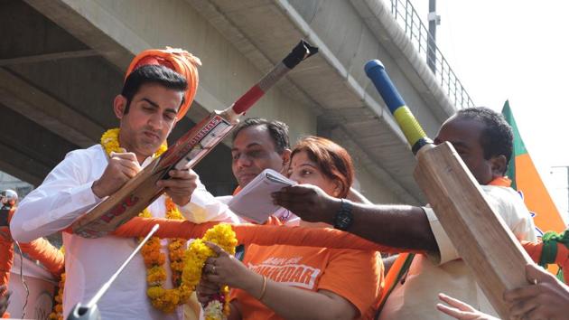 Cricketer-turned-politician BJP candidate from East Delhi Loksabha constituency Gautam Gambhir signs his autograph during the road show at New Ashok Nagar to Trilokpuri in New Delhi.(Mohd Zakir/HT PHOTO)