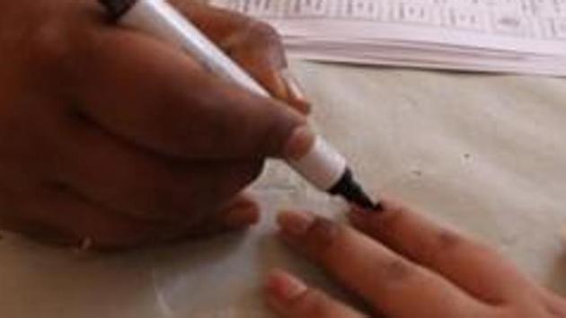 A polling official inks a voter’s finger after she cast her vote.(Puneet Chandhok/HT Photo)