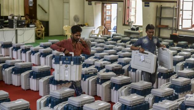 Election officials with Electronic Voting Machines (EVMs) at a distribution centre.(HT file photo)
