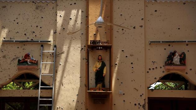 A statue of St. Jude stands on a wall speckled with fragments of shrapnel at St. Sebastian’s Church. One can see the beauty in the broken stained-glass windows. It’s there as the sun shines through the roof’s gaping holes. It’s there in the little statues that refused to fall over, and despite the swarms of police and soldiers who seem to be everywhere now in the streets of the seaside town of Negombo. (Manish Swarup / AP) A statue of St. Jude stands on a wall speckled with fragments of shrapnel at St. Sebastian’s Church. One can see the beauty in the broken stained-glass windows. It’s there as the sun shines through the roof’s gaping holes. It’s there in the little statues that refused to fall over, and despite the swarms of police and soldiers who seem to be everywhere now in the streets of the seaside town of Negombo. (Manish Swarup / AP)