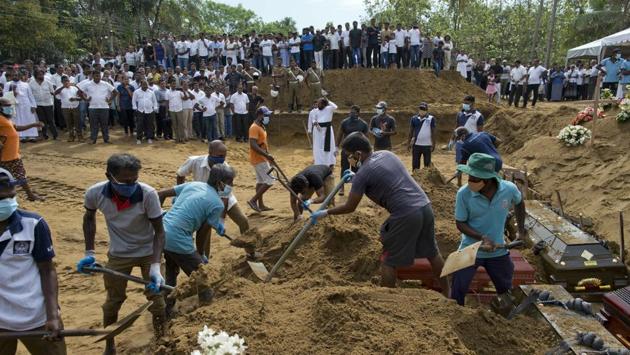 Workers bury coffins during a mass funeral for Easter Sunday bomb blast victims in Negombo. Authorities say a once-obscure militant Muslim group carried out the attacks. (Gemunu Amarasinghe / AP) Workers bury coffins during a mass funeral for Easter Sunday bomb blast victims in Negombo. Authorities say a once-obscure militant Muslim group carried out the attacks. (Gemunu Amarasinghe / AP)