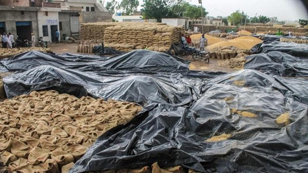 Wheat sacks are covered with tarpaulins during rains at a grain market near Patiala, Wednesday, April 24, 2019.(PTI)