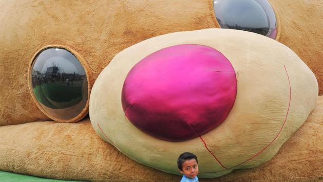 A little boy stands in front of a giant teddy bear measuring more than 20 meters long and weighing 4 tons, which entered the Guiness Book of World Records as the biggest of its kind, in Xonacatlan, Mexico. (Mario Vazquez / AFP)