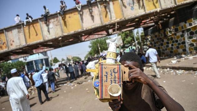 A Sudanese boy uses a fake camera made of cardboard and acts like he is filming during a sit-in outside the army headquarters in the capital Khartoum, Sudan. (Ozan Kose / AFP)