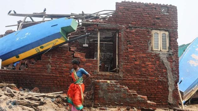 An Indian woman walks next to a damaged building with a fishing boat lodged on its roof along the seafront in Puri in the eastern Indian state of Odisha on May 4, 2019, after Cyclone Fani swept through the area.(AFP)