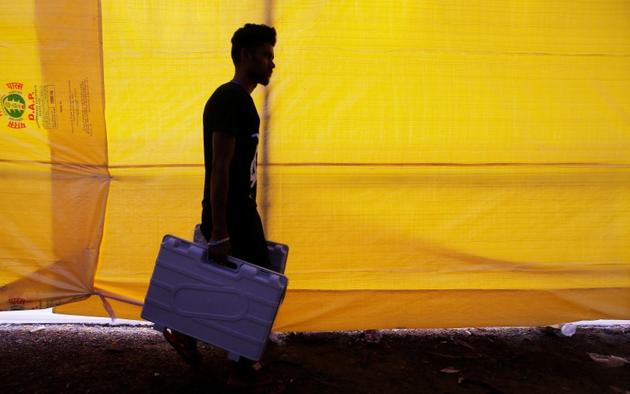 An election staff member carries Electronic Voting Machines (EVM) after collecting them from a distribution centre.(REUTERS)