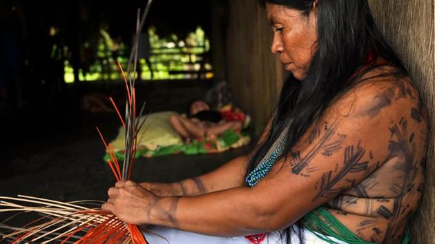“The proper medicines are not coming in. They are too expensive,” says Yenny Cardenas, weaving a basket as she waits in her hut, which is built on stilts over the riverbank. Its roof thrums under heavy rain. She is waiting to board a skiff that will speed her across to the ship with her baby boy, her fifth child. She’s worried about his skin which, for months now, has been covered in sores. (Raul Arboleda  / AFP) 