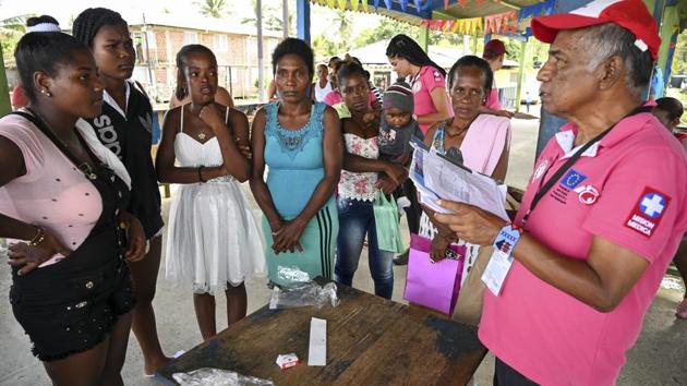 Colombian doctor and teacher Oscar Arley Gomez (R) speaks with locals before the arrival of the hospital ship.  The area has just one medical dispensary, supplying 16,000 people. On the other bank is the wharf at Docordo, a majority Afro-Colombian town lost in the country’s poorest department, Choco -- where nearly 50 percent of the population live in extreme poverty, compared to 17 percent nationally. (Raul Arboleda / AFP) 