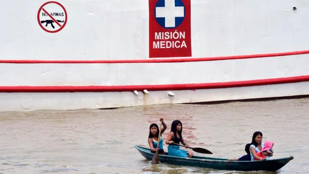 Bearing a white cross on its hull, it’s anchored mid-river, as if honouring its neutrality between these two neighbouring communities -- indigenous and Afro-Colombian -- which do not mix. Another sign -- featuring a machine gun with a ‘X’ over it -- warns that carrying firearms on board is prohibited. (Raul Arboleda / AFP) 