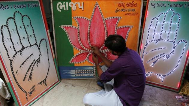 An electrician tests LED-light fitted boards with party symbols of the Bharatiya Janata Party and the Congress(REUTERS)