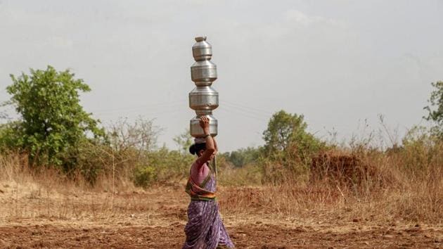 A woman carries multiple pots as she fetches water from a well, in a 'wada' of Dhasai village in Murbad taluk of Thane district. (PTI) A woman carries multiple pots as she fetches water from a well, in a 'wada' of Dhasai village in Murbad taluk of Thane district. (PTI)