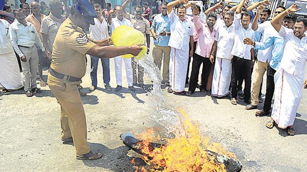 A police officer douses an effigy set ablaze by the BJP workers during a protest against MNM)chief Kamal Haasan at Vadasery near Nagercoil, in Kanyakumari district, on Tuesday, May 14, 2019.(PTI)