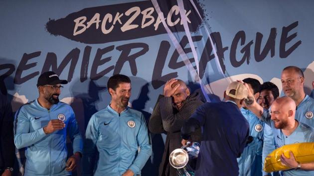 Manchester City's Spanish manager Pep Guardiola (C) shares a joke with his players and coaching staff as they show the Premier League trophy to supporters outside the Etihad Stadium in Manchester(AFP)